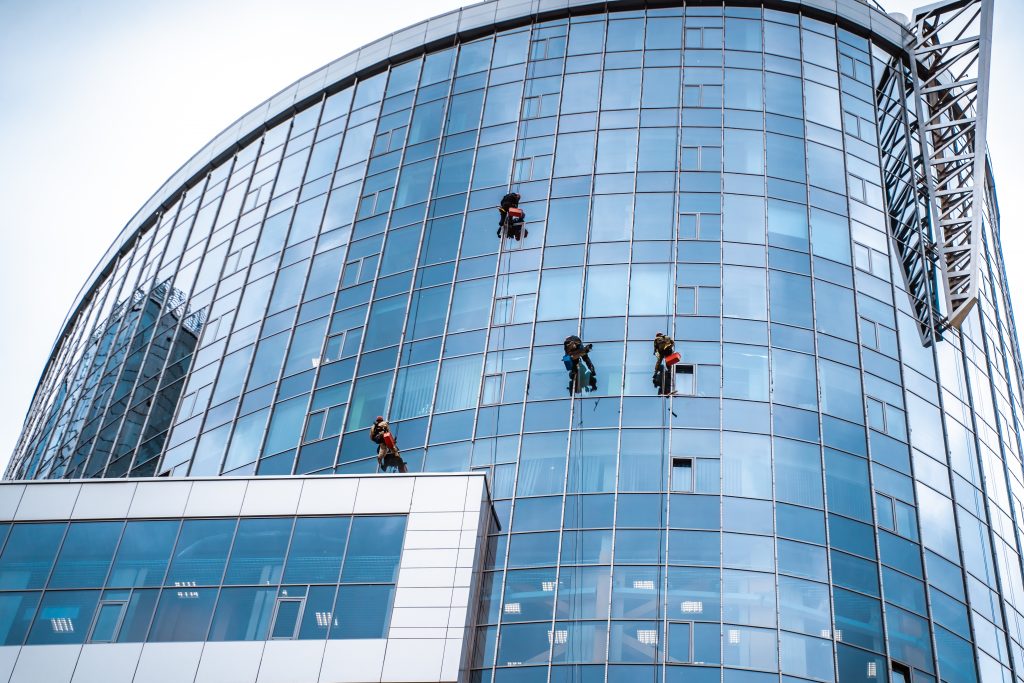 Grupo de trabajadores colgando haciendo una limpieza de trabajos verticales de cristales de difícil acceso